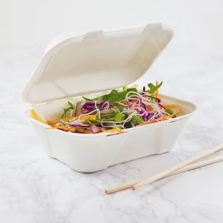 Takeout container with salad and chopsticks on a white surface